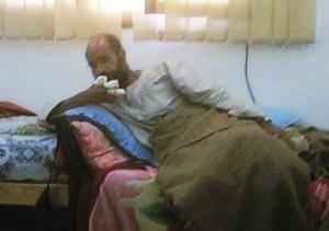الصورة الاولى لسيف الاسلام القذافي بعد اعتقاله ممدا على سرير وتظهر اصابات واضحة في يده اليمنى 	اپ﻿