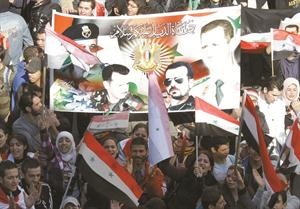 موالون للرئيس بشار الاسد يحملون صورة له ولوالده الراحل في مسيرة مؤيدة بدمشق امس افپ