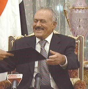 والرئيس صالح مبتسما خلال تسلمه نصا عن المبادرة للتوقيع عليها﻿