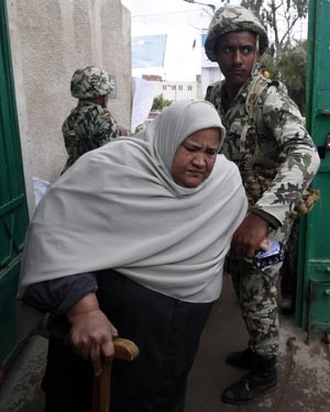 مجند بالجيش المصري يساعد احدى الناخبات على الوصول الى اللجنة الانتخابية
