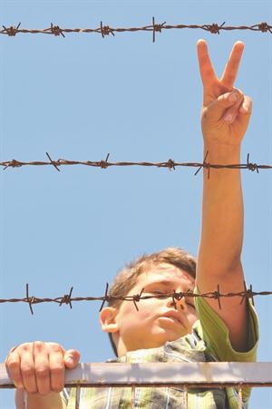﻿طفل سوري لاجئ في مخيم الهلال الاحمر التركي في هطاي بتركيا يرفع علامة النصر﻿