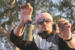 احد المتظاهرين يرفع قنبلة مسيلة للدموع 
