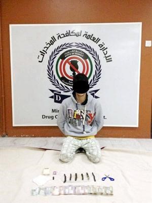 المتهم وامامه كمية الحشيش المضبوطة