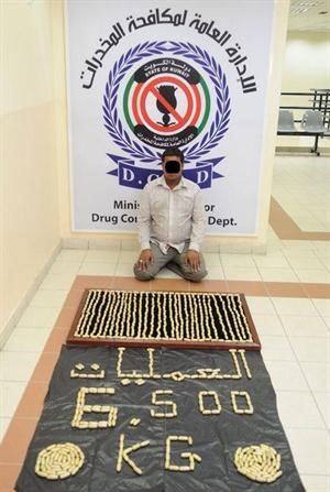 المتهم الاسيوي وامامه الهيروين في مقر الادارة العامة لمكافحة المخدرات﻿