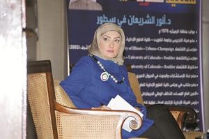 عريفة الندوة وخلفها البرنامج الانتخابي للشريعان
