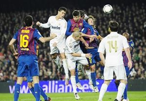 مهاجم ريال مدريد كريستيانو رونالدو يحول الكرة براسه امام مدافعي برشلونة كارليس بويول وجيرار بيكيه اپ