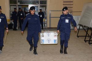 رجلا امن يحملان احد صناديق الاقتراع باتجاه اللجنة الرئيسية