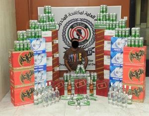 الوافد الاسيوي وامامه الخمور المضبوطة﻿