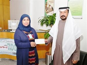 هنادي التركماني تسلم الشيك للمدير المعين لجمعية الظهر عبدالله العازمي
