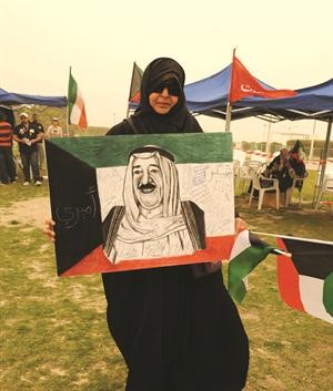 مواطنة تحمل صورة لصاحب السمو عليها تواقيع المشاركين في الحملة﻿