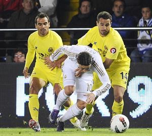 لاعب ريال مدريد مسعود اوزيل يتعرض للمضايقة من مدافع فياريال انخل لوبيز افپ
