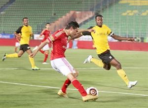 نجم الاهلي محمد بركات يمرر الكرة امام احد لاعبي البن