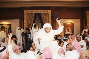 دخالد شخير محمولا على الاعناق رافعا عقاله لرد التحية
