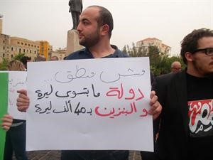 متظاهر لبناني يحمل يافطة تندد بارتفاع اسعار البنزين ﻿