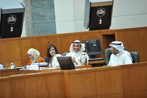 مرزوق الغانم على المنصة متوسطا فريق مكتب اللجنة المالية وتبدو رئيسة مكتب اللجنة حنان القلاف والمستشارة المالية دهالة الحميدي 