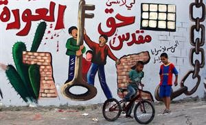 اطفال فلسطينيون بجوار حائط مطلي حديثا ومكتوب عليه حق العودة بمناسبة يوم النكبة 	رويترز﻿