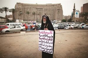 مسن في ميدان التحرير يرفع لافتة منددة بالانتخابات الرئاسية في مصر 