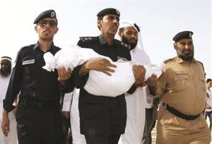 رجل شرطة يحمل جثة احد ضحايا الحريق