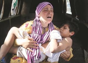 سيدة سورية تحمل طفلها المصاب بنيران القوات السورية خلال هروبهم الى لبنان عبر وادي خالد اپ