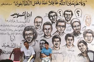 مصريان يجلسان امام حائط مرسوم عليه صور لبعض من شهداء الثورة المصرية امس 	افپ﻿