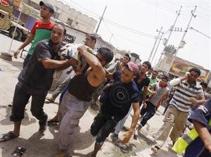 عراقيون يحاولون اسعاف احد المصابين في منطقة الوشاش في بغداد امس	رويترز﻿