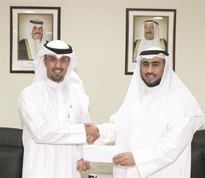 علي البغلي يقدم شيك المساهمة الى مدير المدرسة دعبدالله الملا﻿