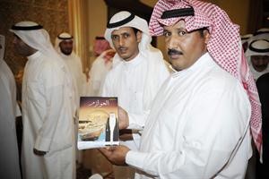 احد الحضور يمسك كتابا عن العوازم خلال الف سنة﻿