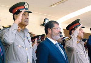 الرئيس المصري دمحمد مرسي متوسطا المشير محمد حسين طنطاوي ورئيس الاركان سامي عنان خلال حفل عسكري امس الاولاپ