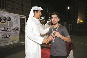 عبدالله المرزوق يقلد الميدالية لاحد اللاعبين
