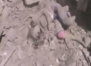 صورة عن فيديو بثه ناشطون لجثة احد الاطفال تحت انقاض القصف في الرستن بحمص