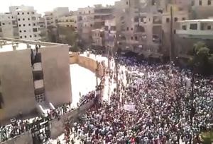 متظاهرون في حي صلاح الدين بحلب واحدهم يرفع علم الثورة على مدرسة