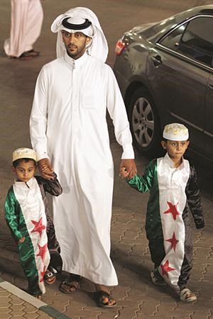 سعودي يصطحب ولديه مرتديين علم الثورة للتبرع للشعب السوريافپ