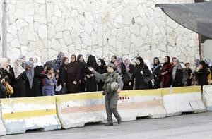 جندية اسرائيلية تراقب حشدا من الفلسطينيات اللواتي ينتظرن الدور لدخول الاقصى الشريف	اپ﻿