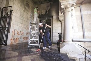 عاملان فلسطينيان ينظفان كنيسة اللطرون التي احرقها مستوطنون متطرفون امس الاول	افپ﻿