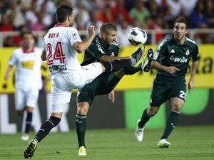 مهاجم ريال مدريد كريم بنزيمة يسدد الكرة بملاحقة مدافع اشبيلية توماس بوتيا رويترز
