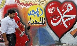 مصري يمر امام جدار في شارع محمد محمود بالقرب من التحرير مكتوب عليه محمد رسول الله صلى الله عليه وسلم و المجد للشهداء﻿