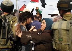 امراة فلسطينية تدفع جنديا اسرائيليا خلال احتجاج في بيت لحم ضد الجدار العازل الاسرائيلي امس افپ