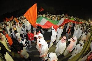 علم الكويت مرفوعا بايدي المشاركين في المسيرة﻿