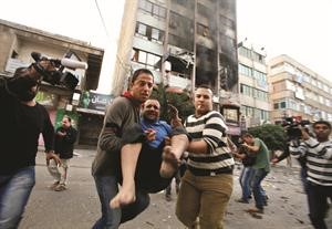 فلسطينيون يسعفون جريحا بعد غارة اسرائيلية على مبنى يحوي مكاتب اعلامية في غزة	رويترز﻿