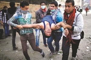 متظاهرون يحملون احد المصابين في ميدان التحرير