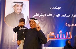 الخرافي حاملا طفلا من ابناء الدائرة الثانية ويرفعان علامة النصر﻿