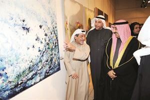 الخرافي يستمع من احد الفنانين لشرح عن مضمون احدى لوحاته﻿