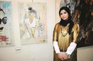 الفنانة فاطمة دشتي امام لوحاتها﻿