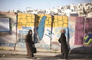 فلسطينيتان تسيران بجانب حائط رسم عليه خريطة فلسطين في الخليل رويترز