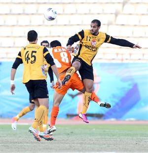 لاعب القادسية بدر المطوع يحصل على الكرة قبل مشاري العازمي﻿