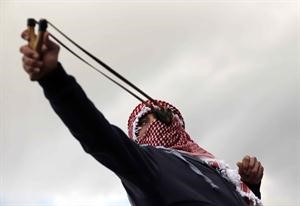 متظاهر فلسطيني يرمي قوات الاحتلال بالحجارة خلال مواجهات عند سجن عوفر	رويترز﻿
