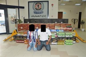 المتهمان وخلفهما الخمور المضبوطة