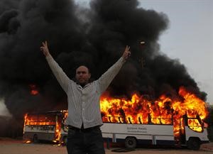 معارض لـ الاخوان المسلمون يرفع شارة النصر عقب احراق احدى حافلات الجماعة امس الاول اپ