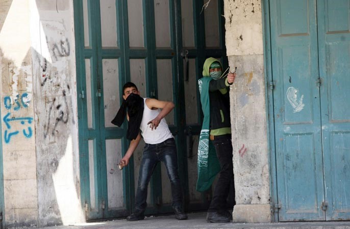 فلسطينيان يقذفان الحجارة على القوات الاسرائيلية خلال مظاهرات امس للتنديد بوفاة الاسير ابوحمديةاف پ