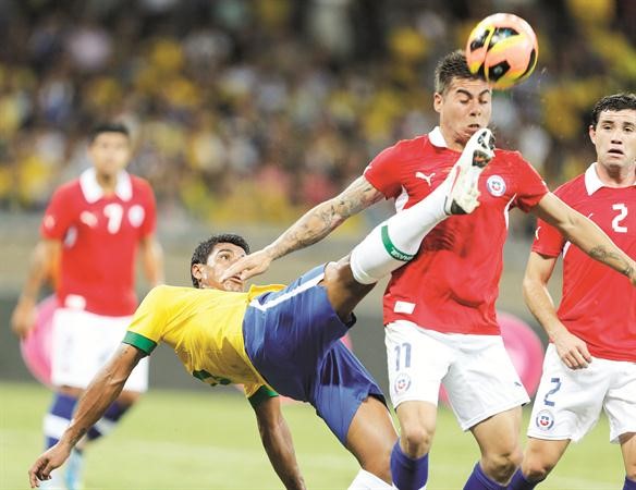 لاعب منتخب البرازيل باولينيو يسدد الكرة من امام التشيلي ادواردو فارغاس رويترز﻿